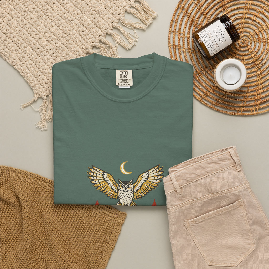 Blue Spruce After Dark Owl Tee laid flat next to a woven basket and folded clothes